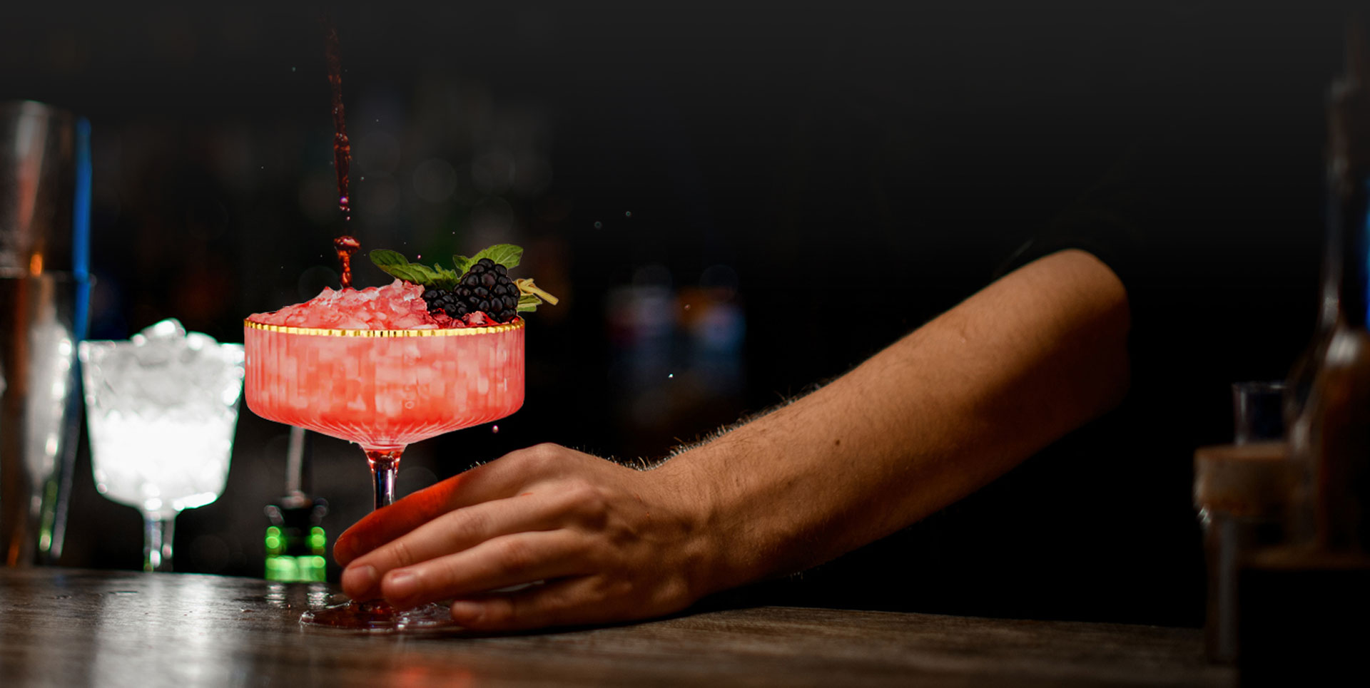 Bartender mixing a mocktail in a fancy gold rimmed glass.